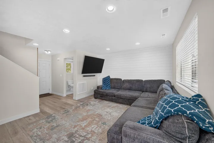 Recessed lighting, wood-finish flooring, white shiplap accent wall, white window blinds, and a white interior door
