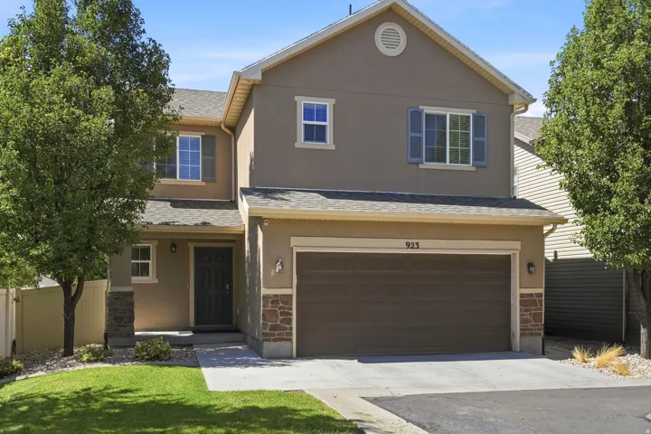 Two-story stucco exterior with stone accents, attached two-car garage, and a covered front entry