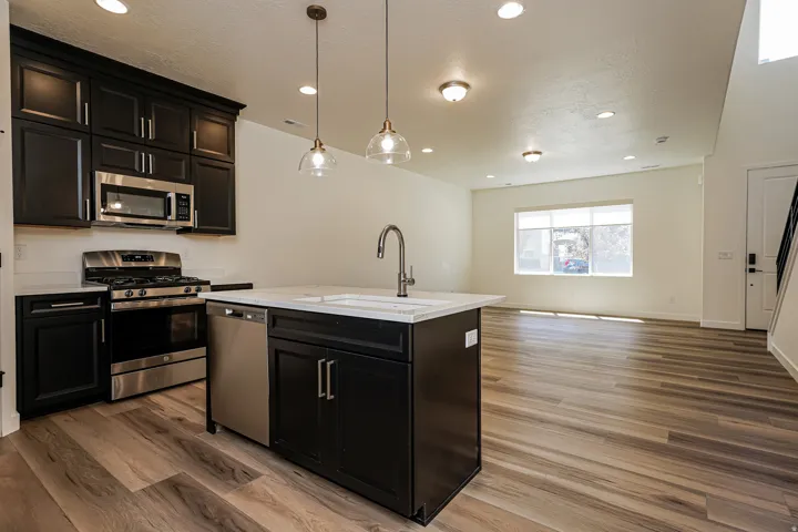 Open-concept living space with wood-finish flooring, a kitchen island, stainless steel appliances, and recessed lighting