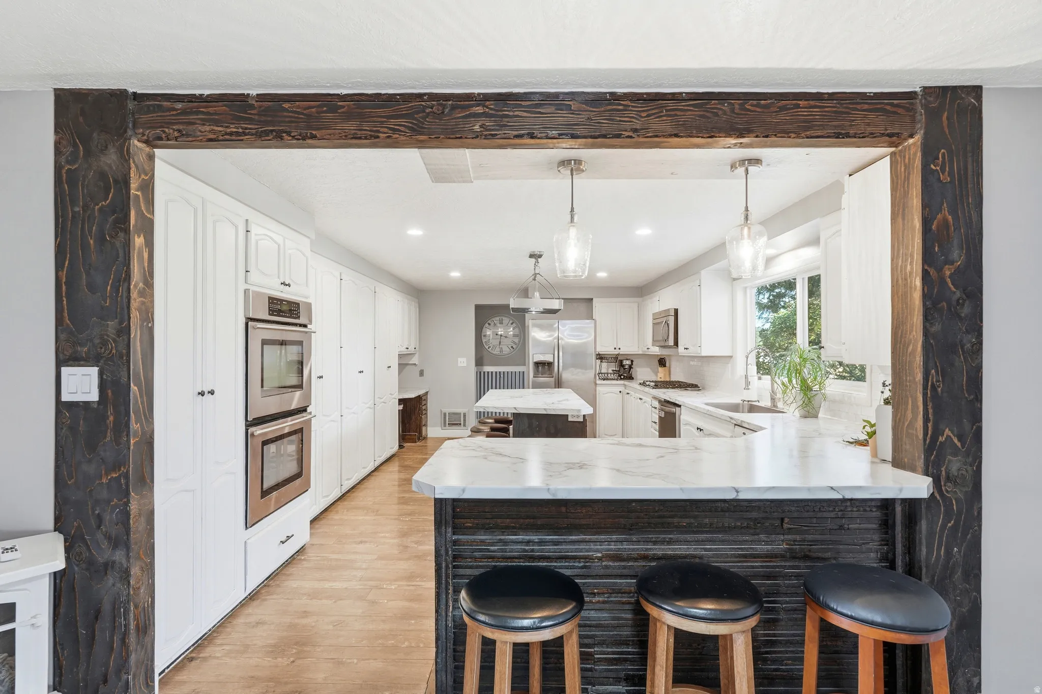 Kitchen featuring white cabinetry, wood-finish flooring, recessed lighting, and a kitchen island with stone countertop