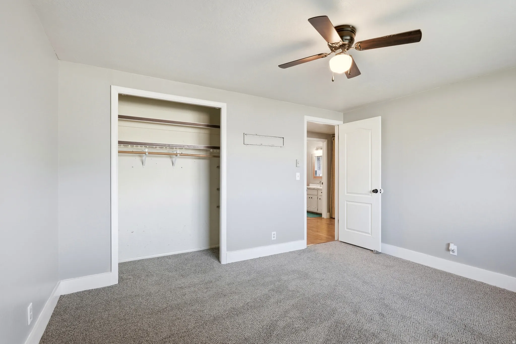 Carpeted flooring, light grey wall paint, white trim, and a ceiling fan with integrated lighting