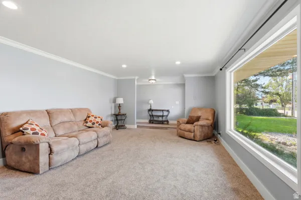 Expansive window providing abundant natural light, crown molding detailing, recessed ceiling lighting, and neutral wall tones