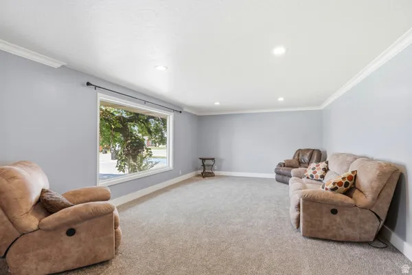 Expansive living area featuring carpet flooring, recessed lighting, a large picture window, and crown molding
