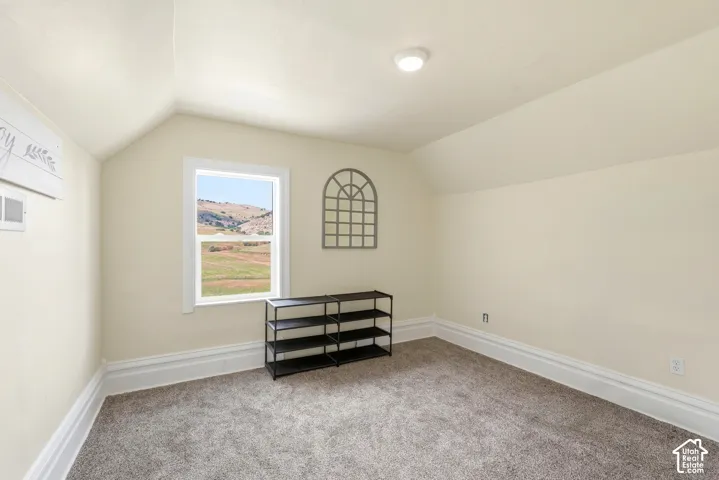 Carpeted room with a single window, sloped ceilings, and white trim
