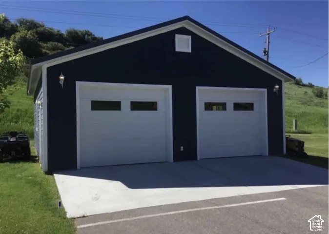 Detached structure featuring dark-colored siding, two garage doors with window panels, and concrete driveway