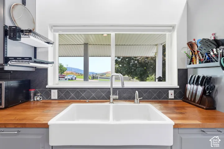 Wood-finish countertops, ceramic farmhouse sink with a gooseneck faucet, and diamond-patterned tile backsplash