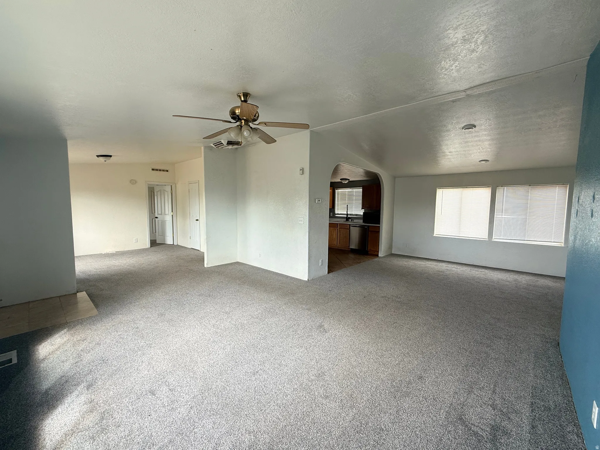 Carpeted living area with overhead ceiling fan and recessed lighting