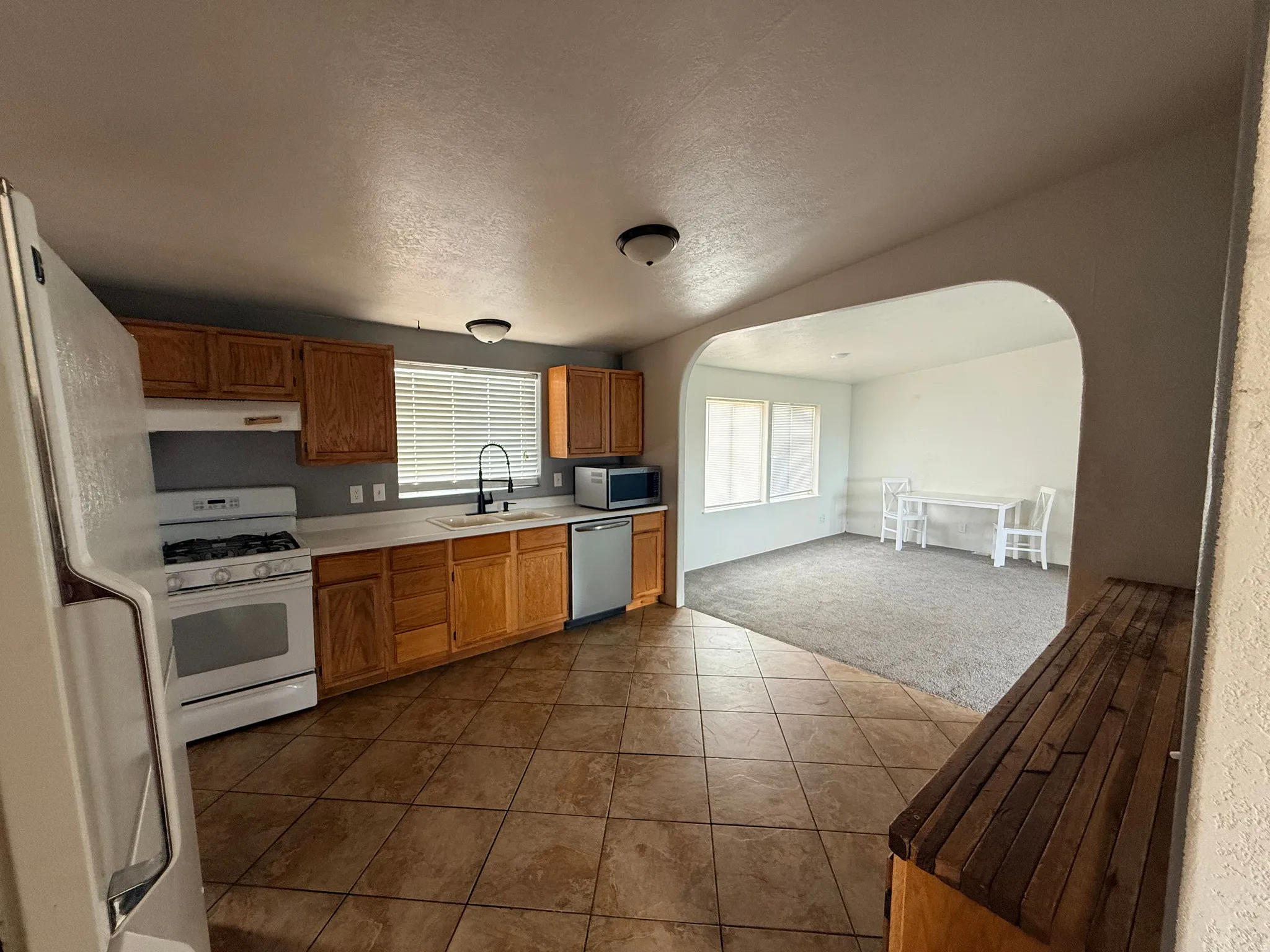 Kitchen featuring tile flooring, wood cabinetry, a gas range, and a stainless steel dishwasher