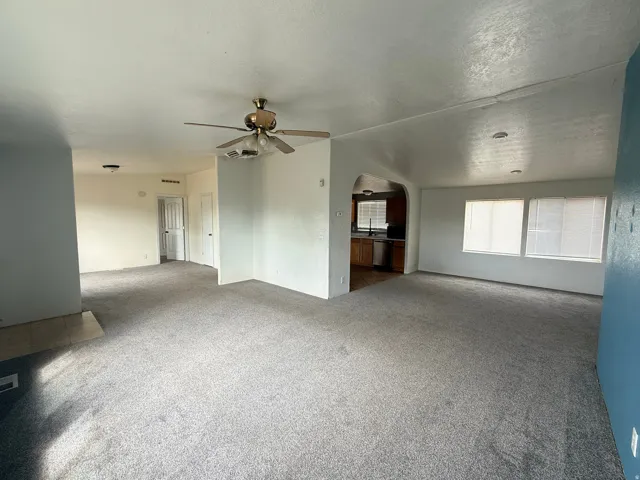 Carpeted living area with overhead ceiling fan and recessed lighting