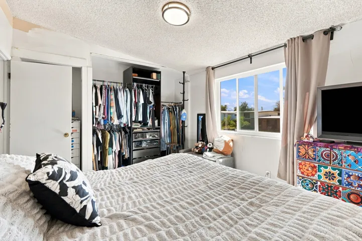 Recessed lighting fixture, light-toned wall paint, built-in closet system, white window frame, and neutral curtains