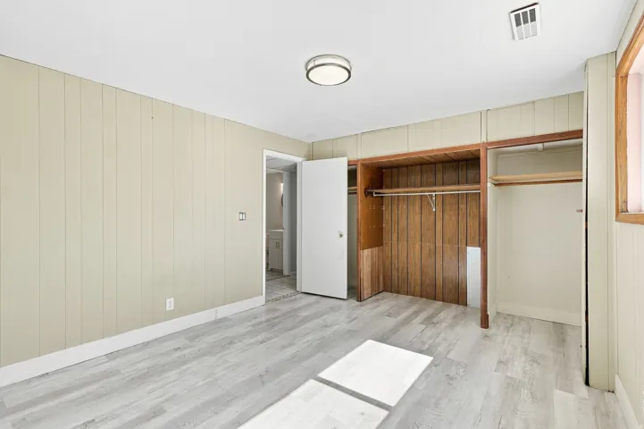 Light wood-finish flooring, paneled wall finishes, and a flush mount ceiling light