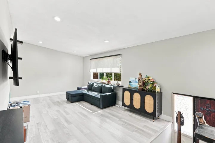Recessed lighting illuminates this room featuring wood-finish flooring