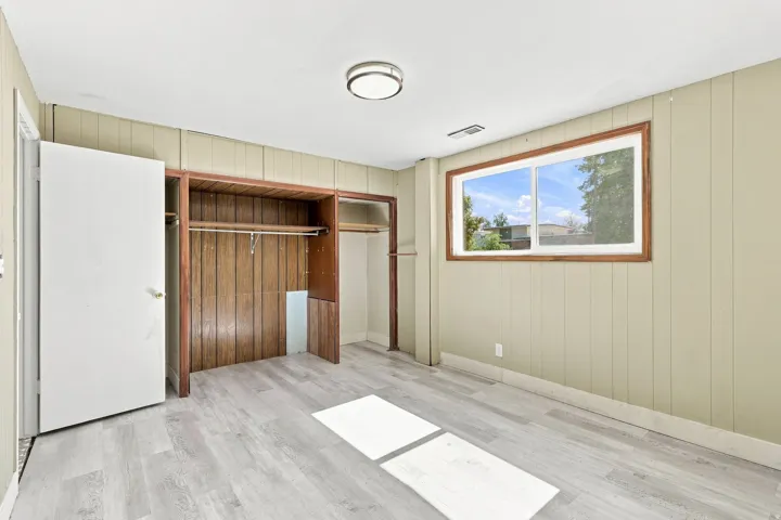 Wood-finish flooring, built-in open shelving, and a prominent window with wood trim