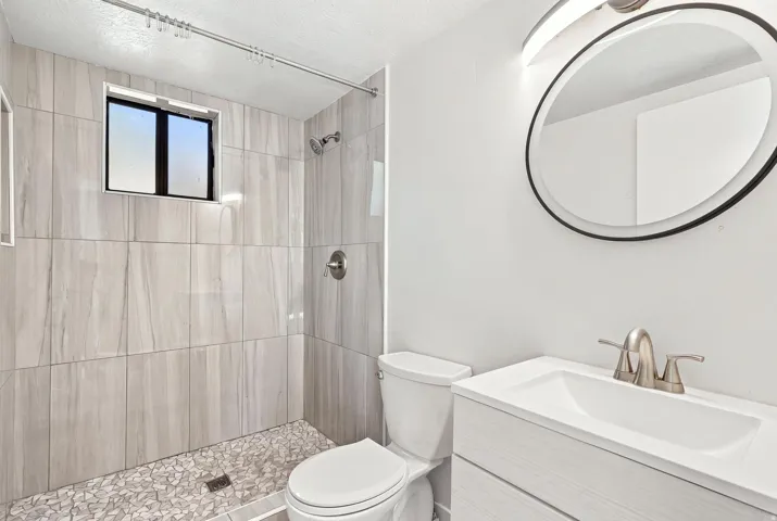Walk-in shower with large format tile walls and pebble floor