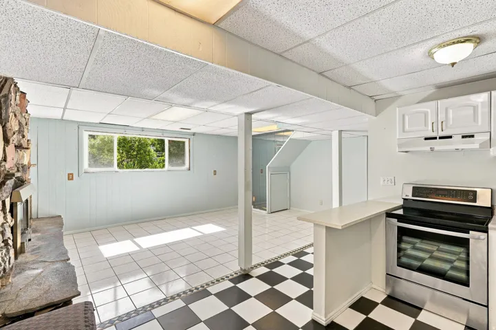Spacious room featuring a stone fireplace, white tile flooring, and a window