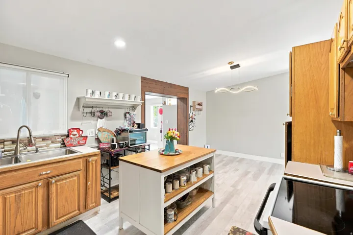 Kitchen featuring wood-finish cabinetry, stainless steel sink, and light-toned backsplash