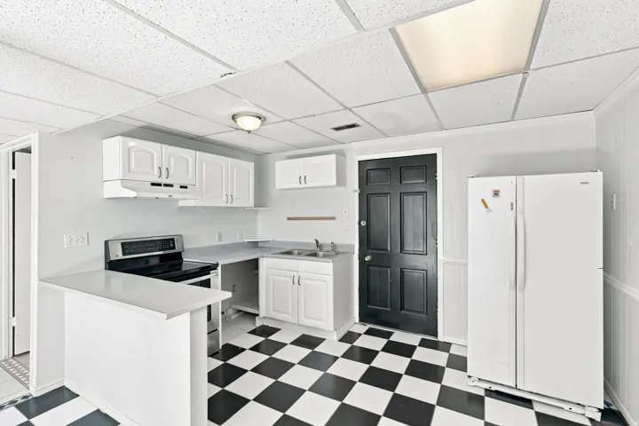 Kitchen featuring white cabinetry, black and white checkered flooring, a stainless steel range, and a breakfast bar