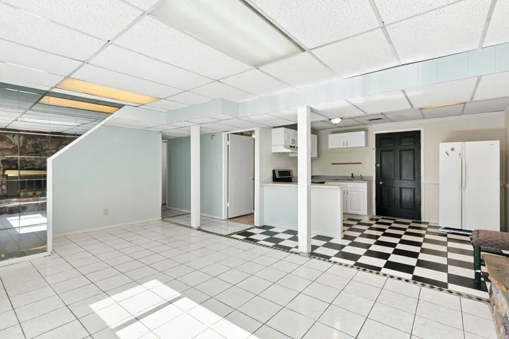 Tile flooring, white cabinetry, black and white checkered flooring, exposed stone feature, drop ceiling with recessed lighting