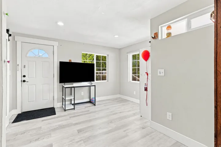 Light wood-finish flooring, recessed lighting, and a white paneled entry door with an arched window