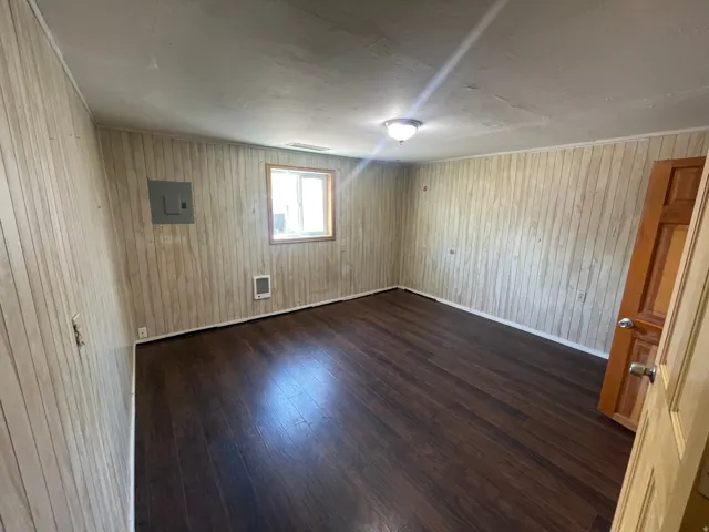 Wood-finish flooring, paneled wall finishes, and a single window offering natural light