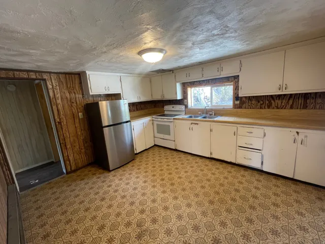 Kitchen featuring white cabinetry, wood-finish countertops, stainless steel refrigerator, and patterned flooring