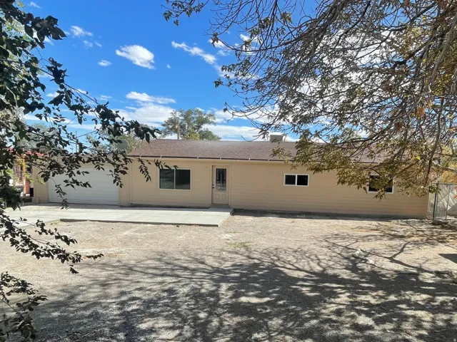 Expansive backyard area featuring a concrete patio, mature trees, and a chain-link fence