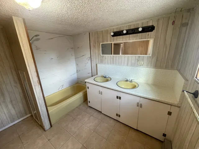 Dual basin vanity with integrated countertop, enclosed cabinetry, full-width mirror, and overhead lighting