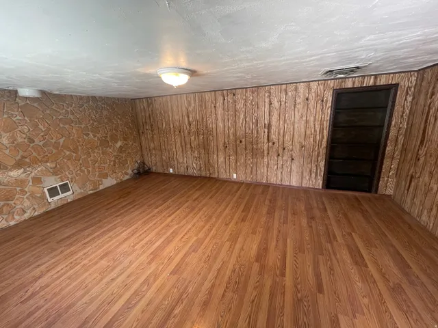 Wood-finish flooring throughout, featuring a stone accent wall, wood paneling, and an integrated built-in bookshelf