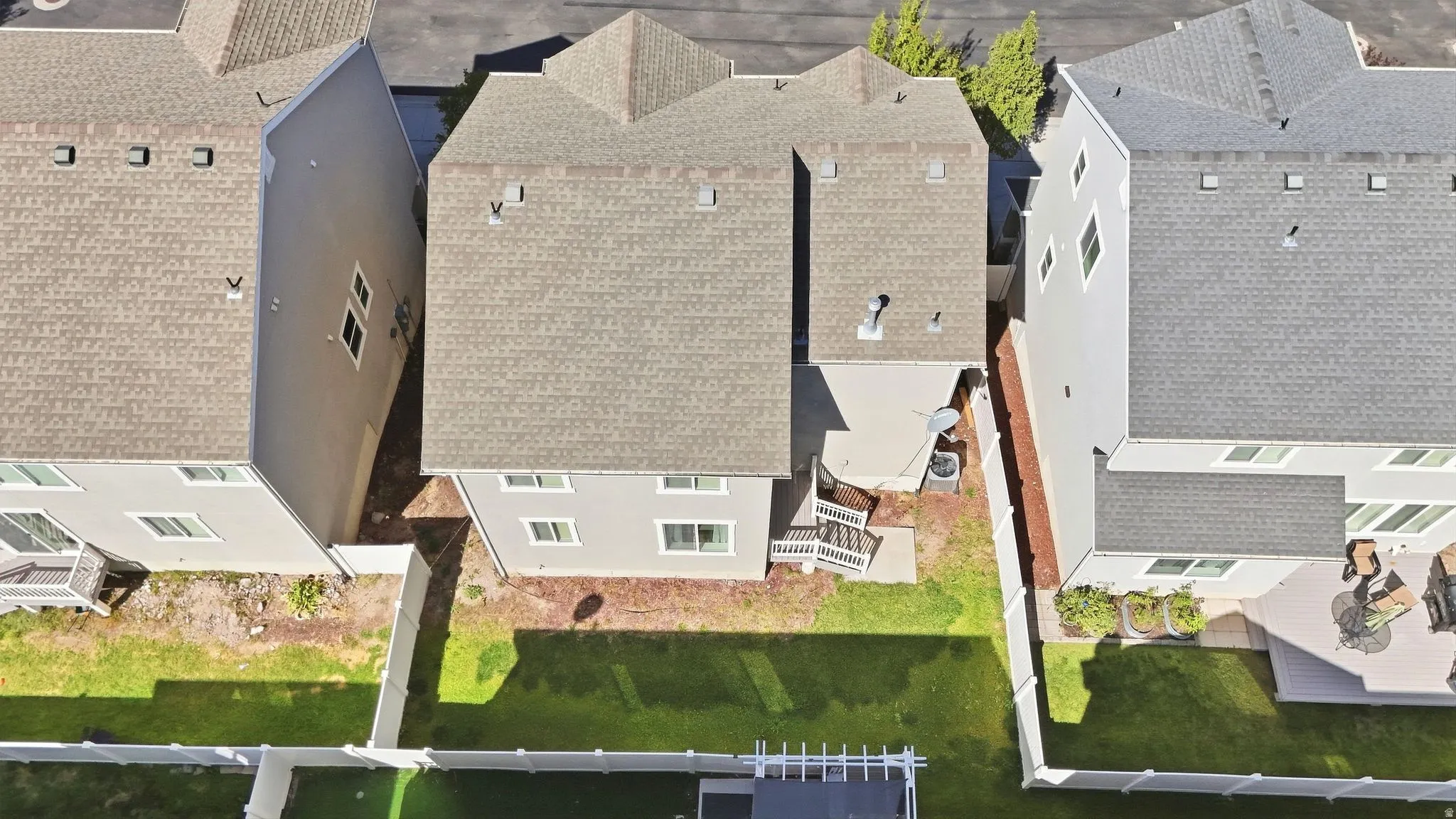 Manicured rear lawn with a white privacy fence, an elevated deck, and a concrete patio