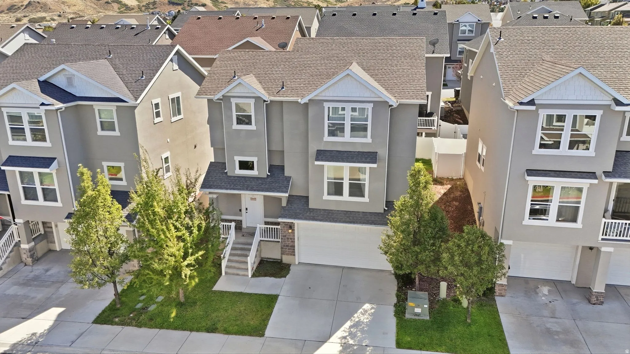 Multi-level residence featuring a two-car garage, front entry porch, and mature landscaping