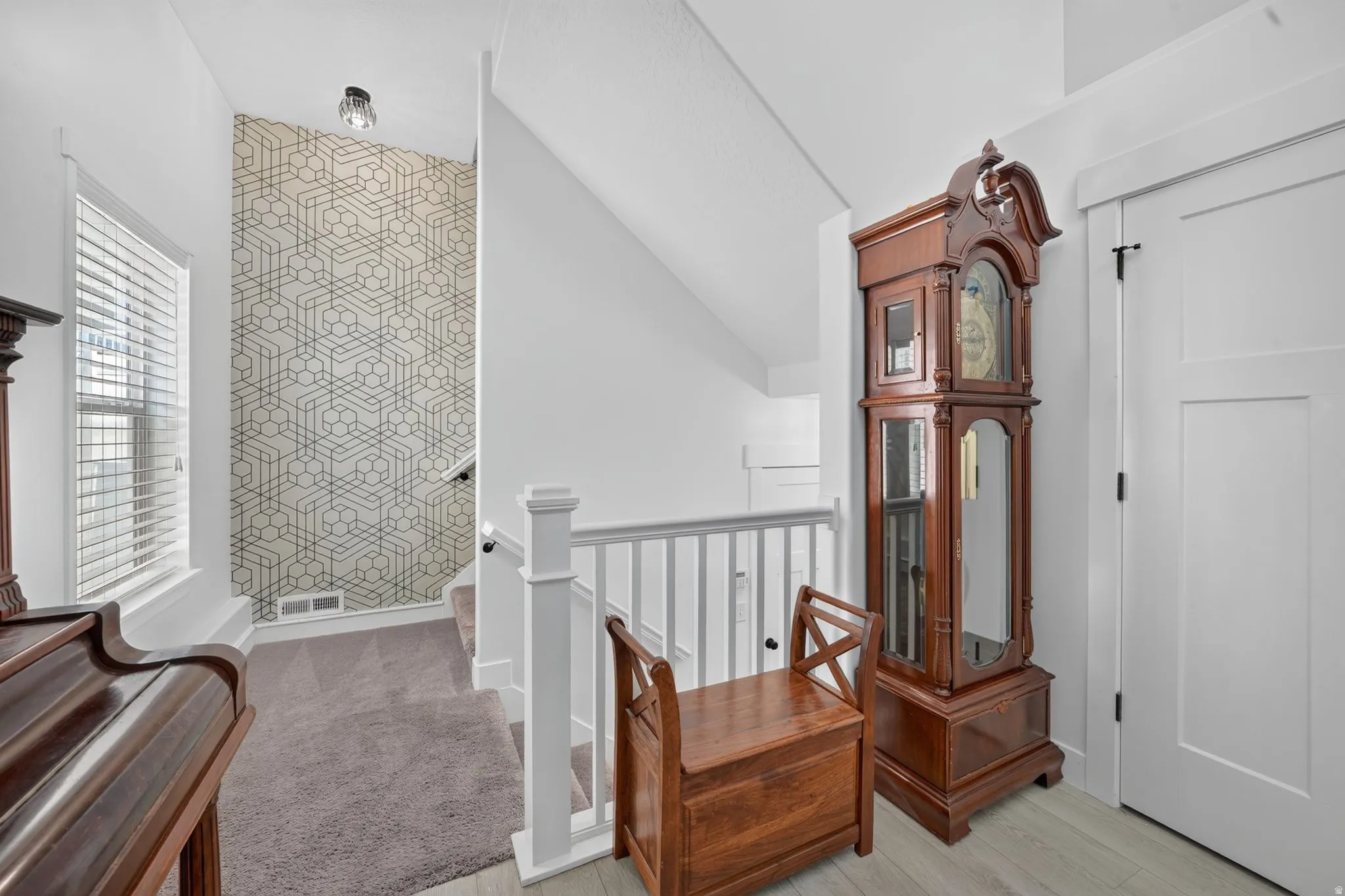 White painted balustrade with square newel posts, patterned accent wall, recessed lighting, and a window with horizontal blinds