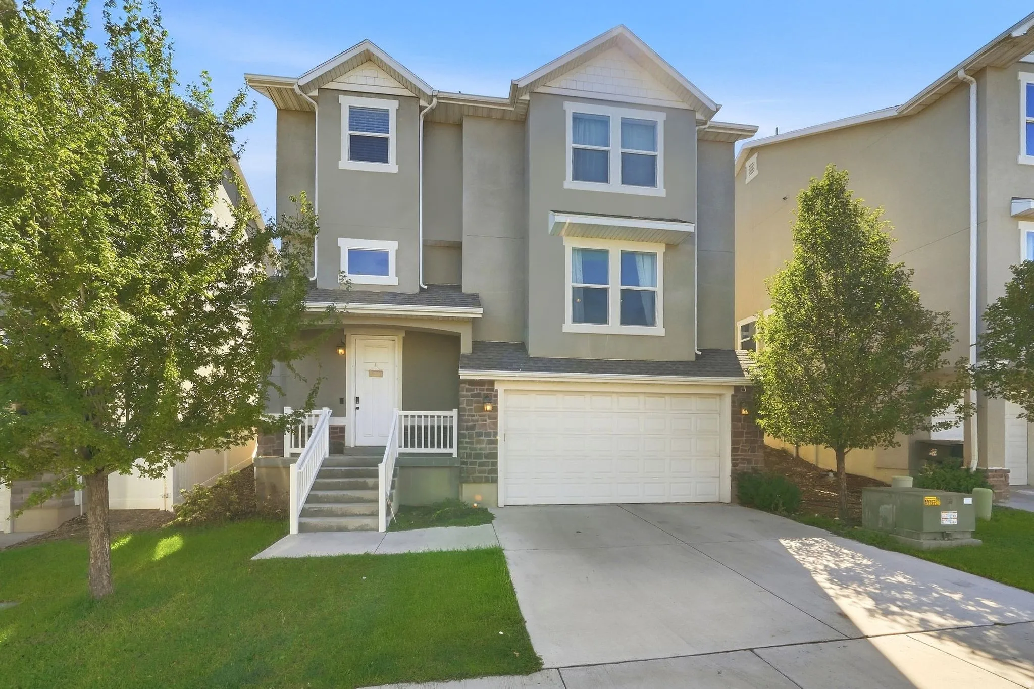 Multi-story stucco exterior with decorative gables, stone accents, and an attached garage