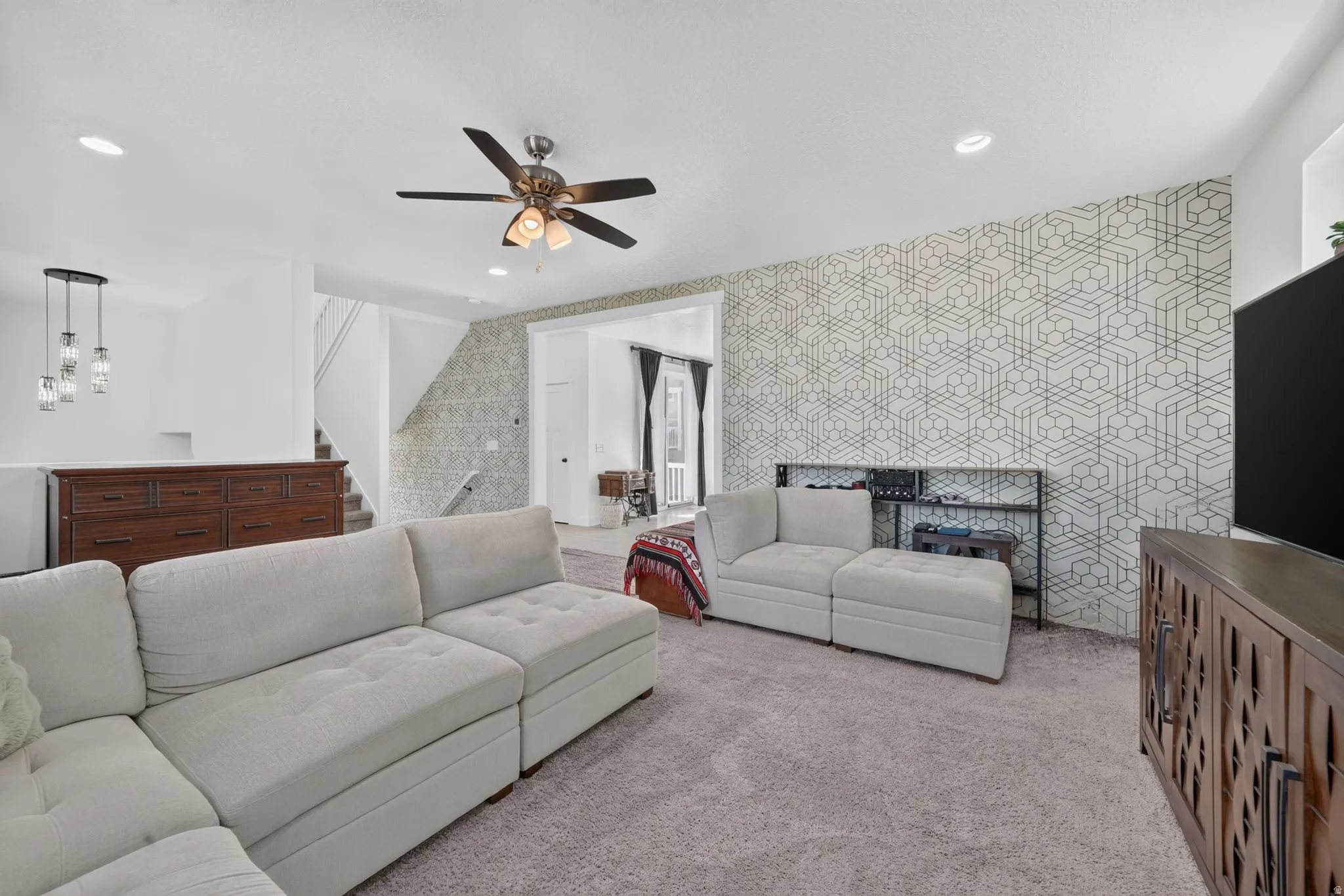 Recessed ceiling lighting, ceiling fan fixture, geometric accent wall, and a staircase with a landing