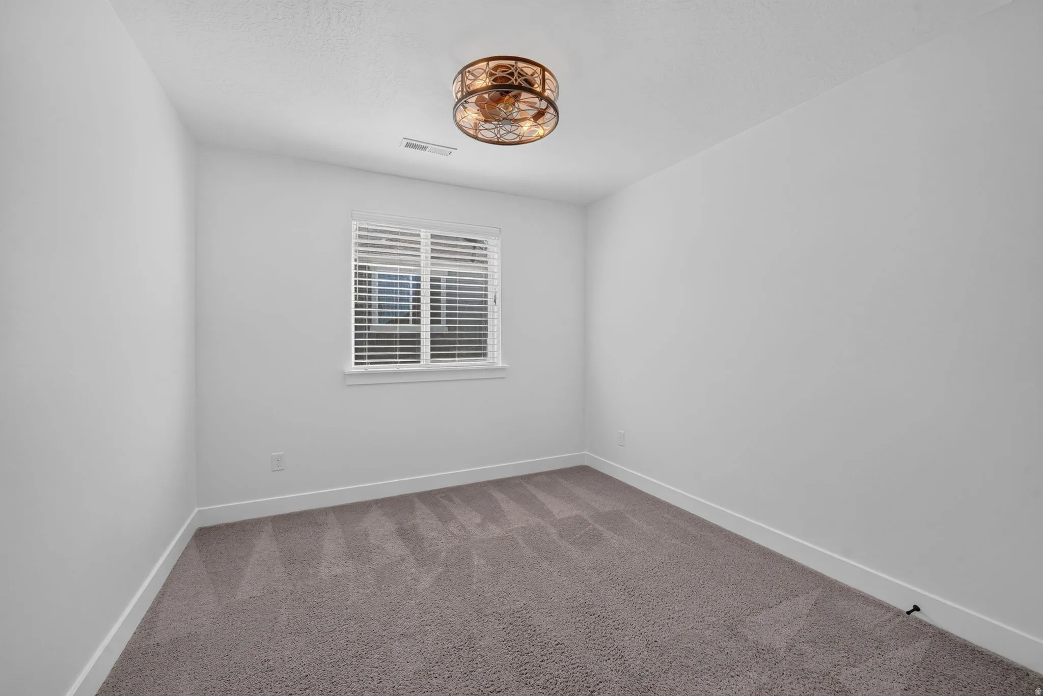 Plush gray carpeting, white walls, white window trim, horizontal blinds, and a decorative ceiling light fixture