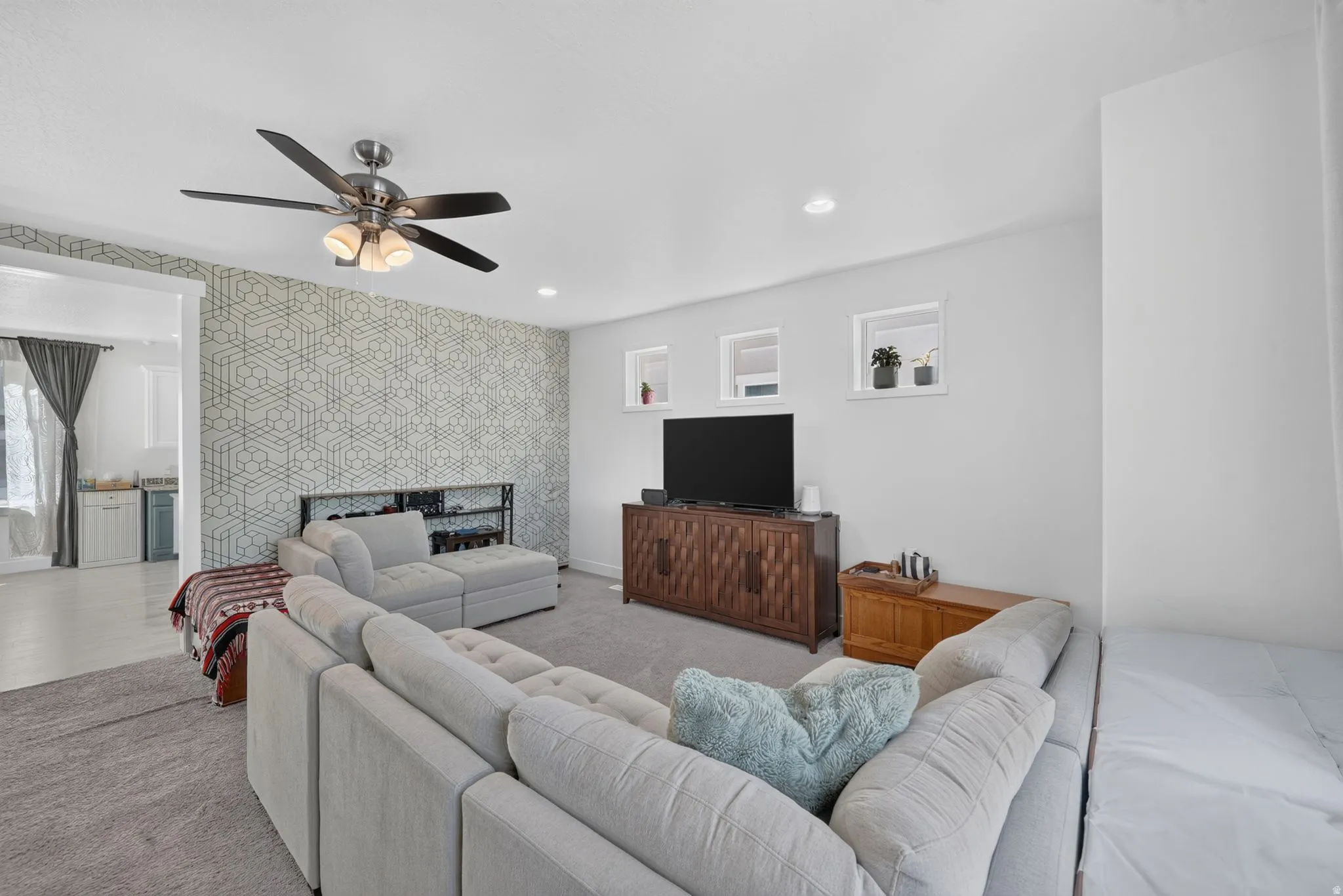 Recessed lighting, ceiling fan, accent wall with geometric pattern, built-in shelving, and multiple windows