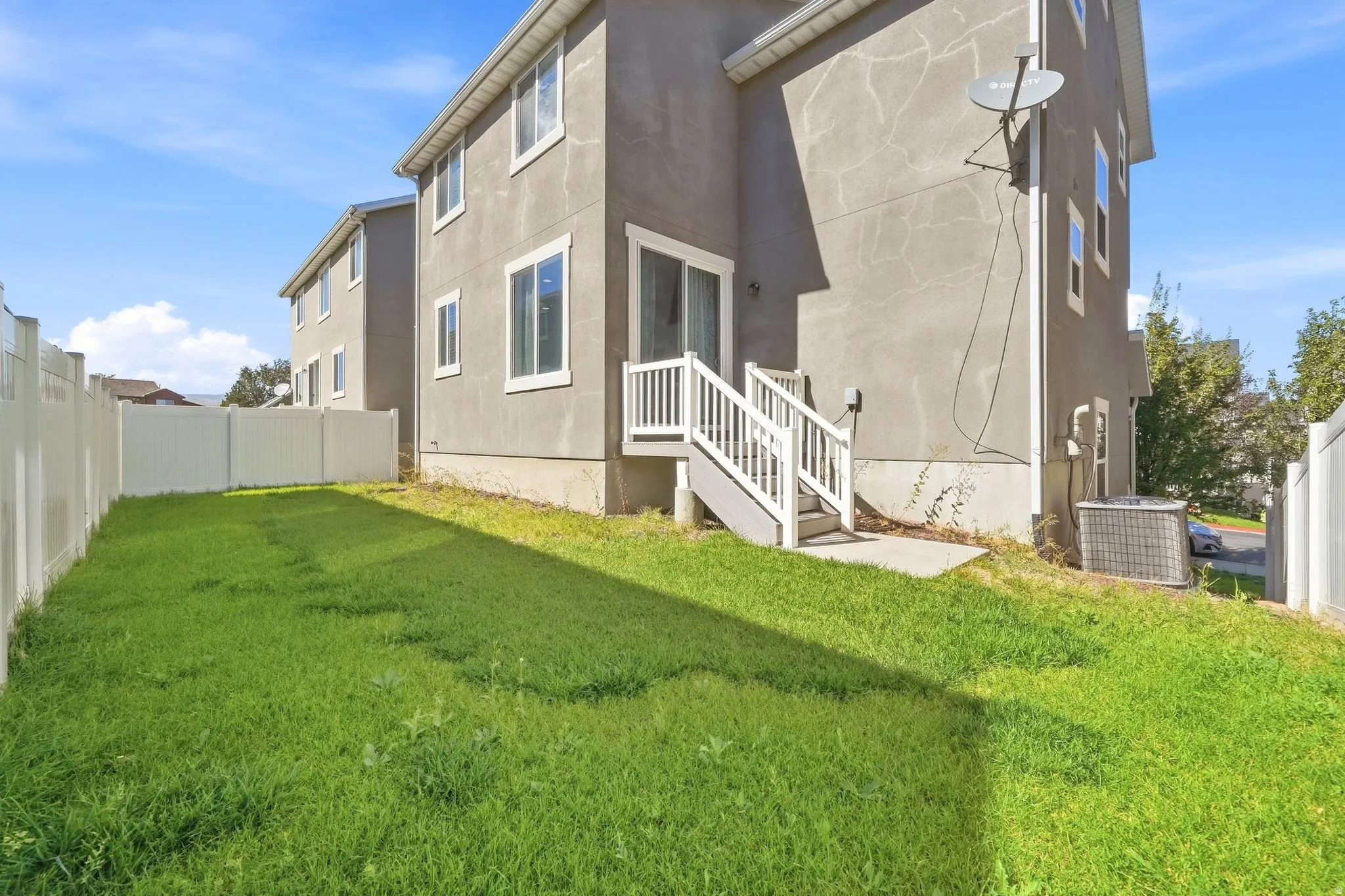 Private backyard with a full vinyl fence, grass lawn, ground-level patio, and exterior stairs leading to a sliding glass door