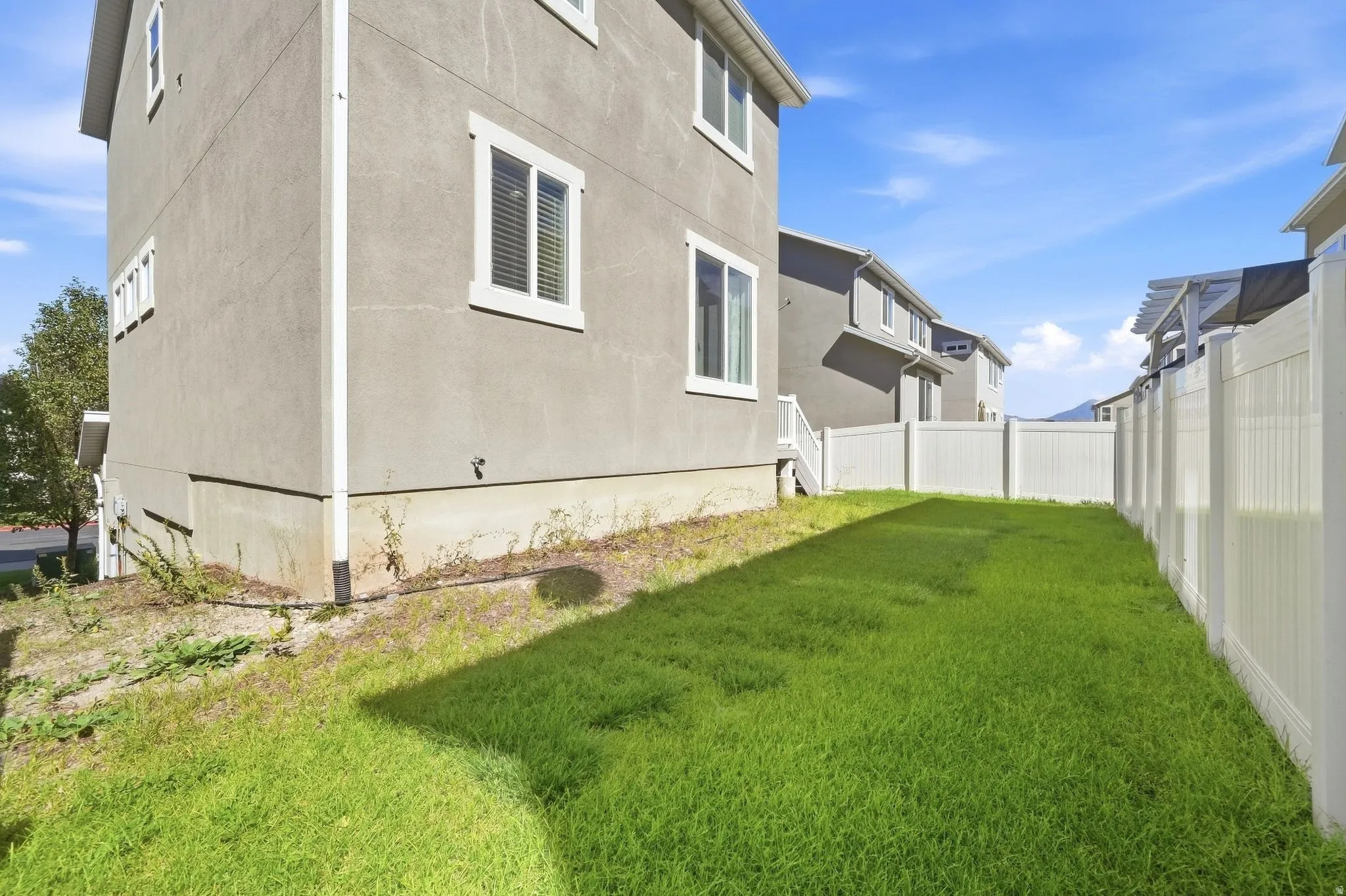 Fully fenced backyard featuring a grassy area and stucco exterior