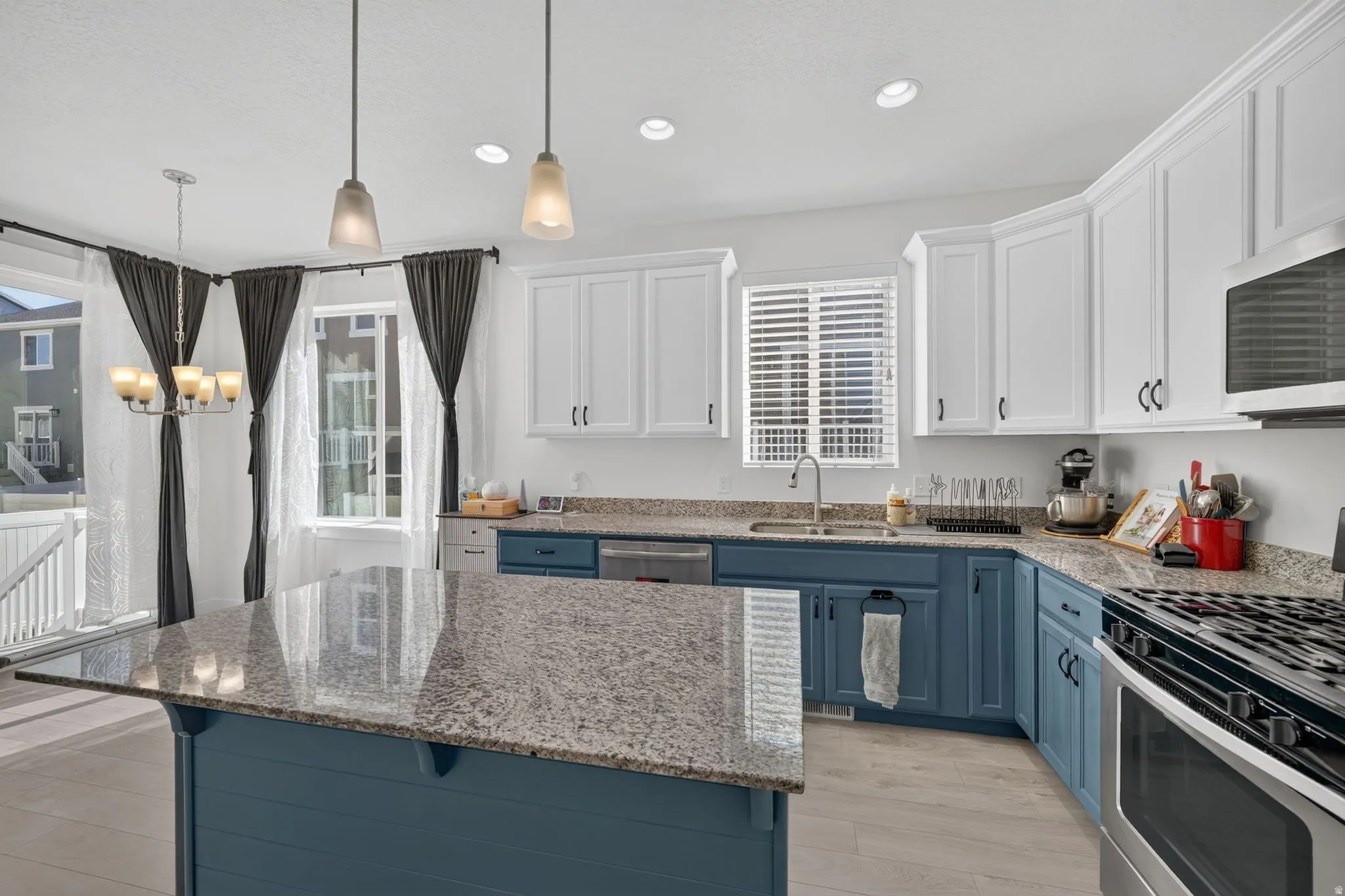 Kitchen featuring a large island with a stone countertop, two-tone cabinetry, stainless steel appliances, and wood-finish flooring