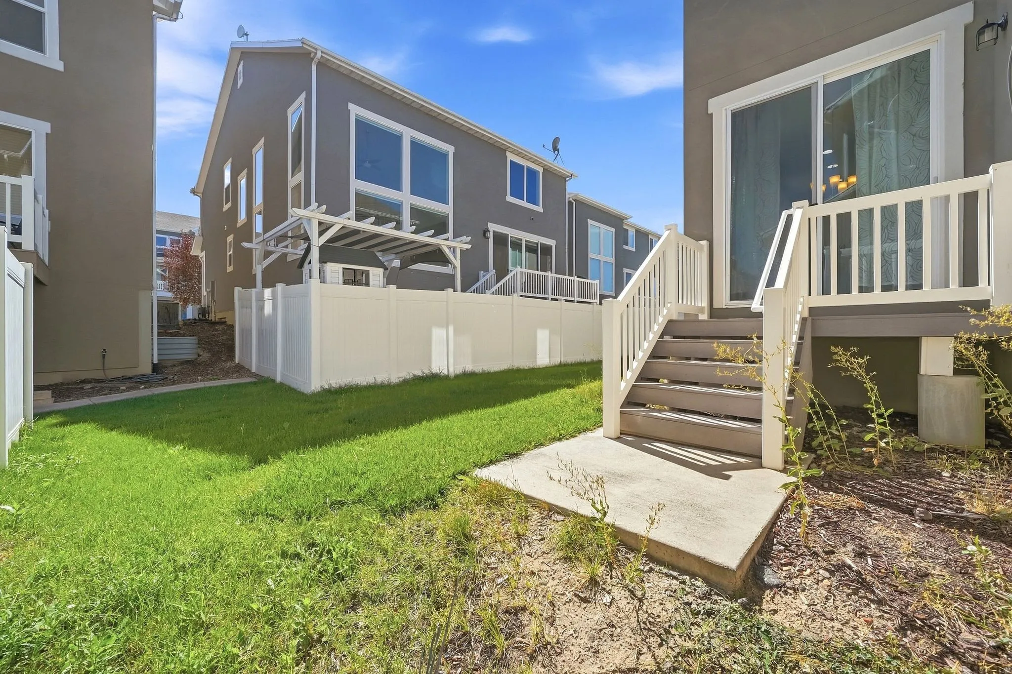 Rear yard with a concrete patio, wooden stairs, and a sliding glass door