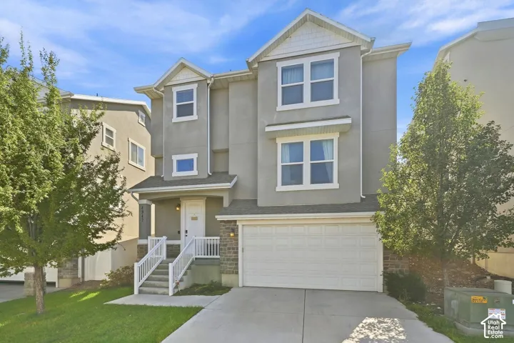 Stucco exterior with gabled roof lines, white trim accents, and a two-car garage