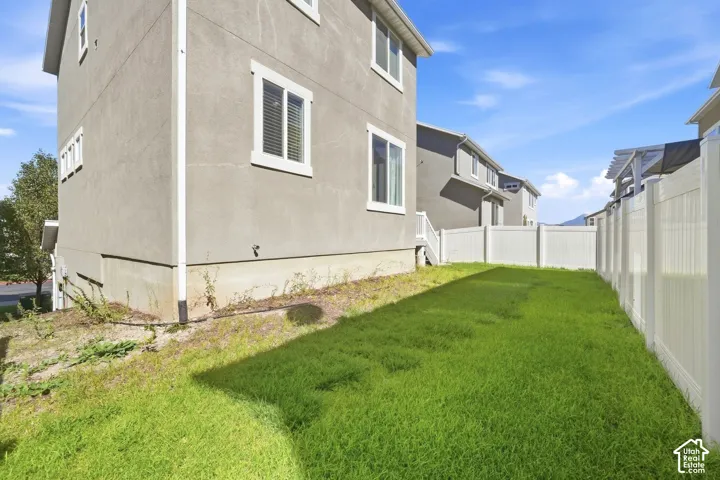 Fully fenced backyard featuring a grassy area and stucco exterior