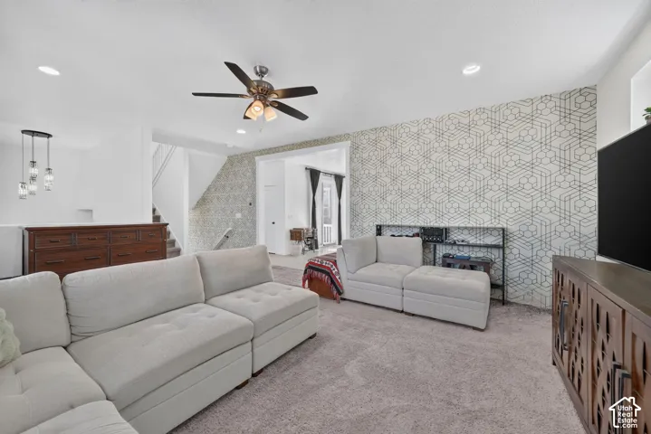 Recessed ceiling lighting, ceiling fan fixture, geometric accent wall, and a staircase with a landing