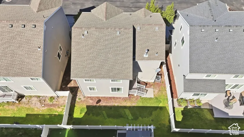 Manicured rear lawn with a white privacy fence, an elevated deck, and a concrete patio