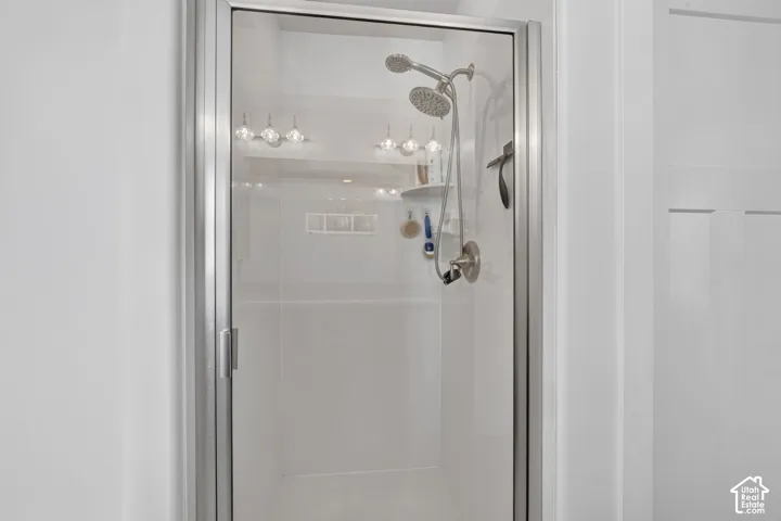 Glass-enclosed shower with brushed nickel fixtures and a built-in shelf