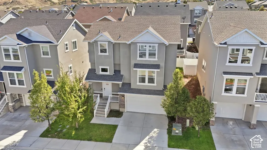 Multi-level residence featuring a two-car garage, front entry porch, and mature landscaping