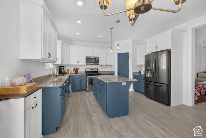 Kitchen featuring a central island, two-tone cabinetry, stainless steel appliances, granite countertops, and wood-finish flooring