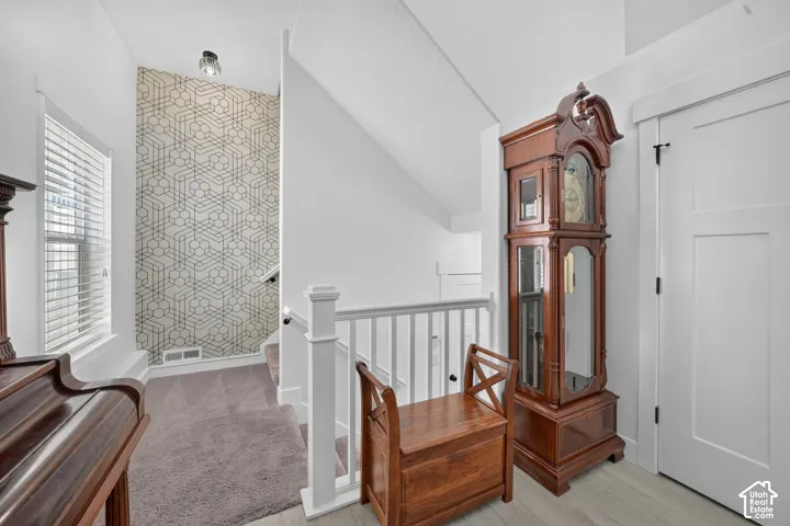 White painted balustrade with square newel posts, patterned accent wall, recessed lighting, and a window with horizontal blinds