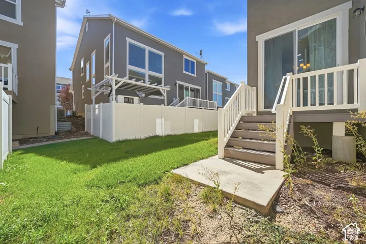 Rear yard with a concrete patio, wooden stairs, and a sliding glass door