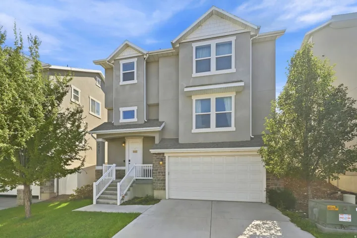 Stucco exterior with gabled roof lines, white trim accents, and a two-car garage