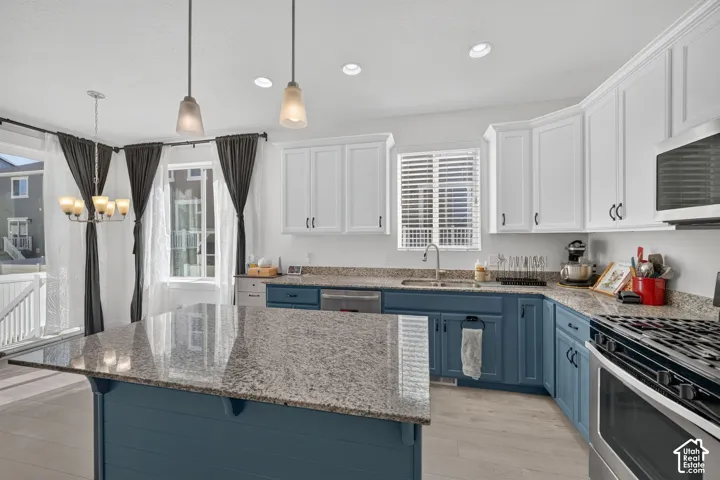 Kitchen featuring a large island with a stone countertop, two-tone cabinetry, stainless steel appliances, and wood-finish flooring